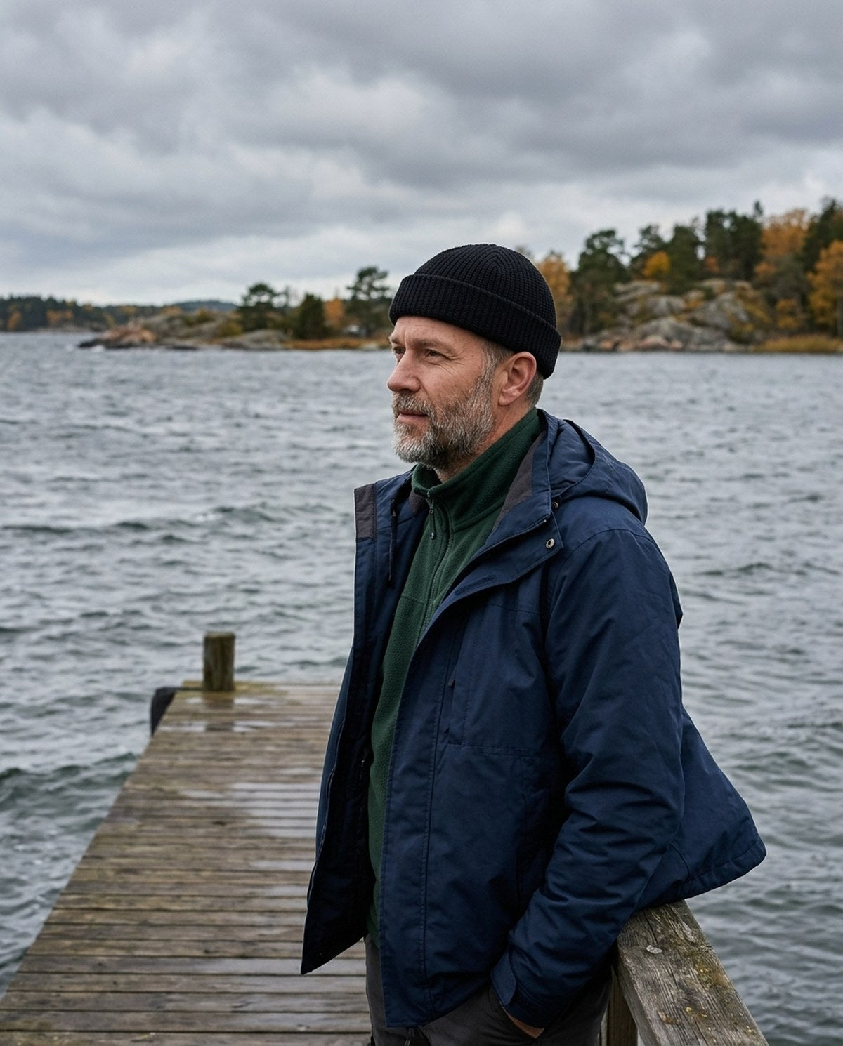 Mann i svart fisherman-lue på en brygge ved sjøen